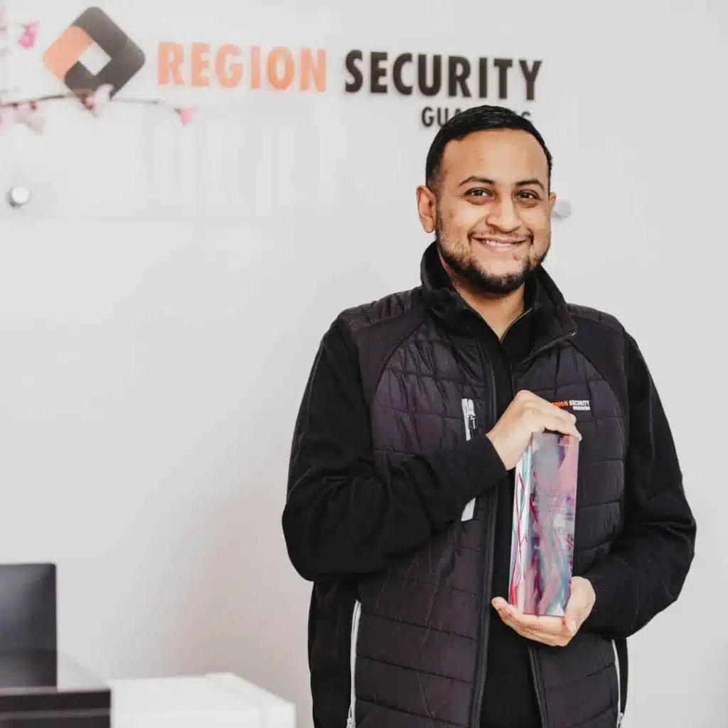 Zachariah Islam, Managing Director of Region Security Guarding, is smiling and holding the Region Security Guarding award.