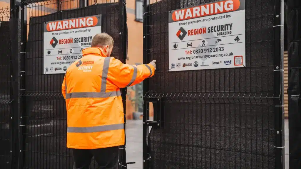 A security guard closing a site entrance gate