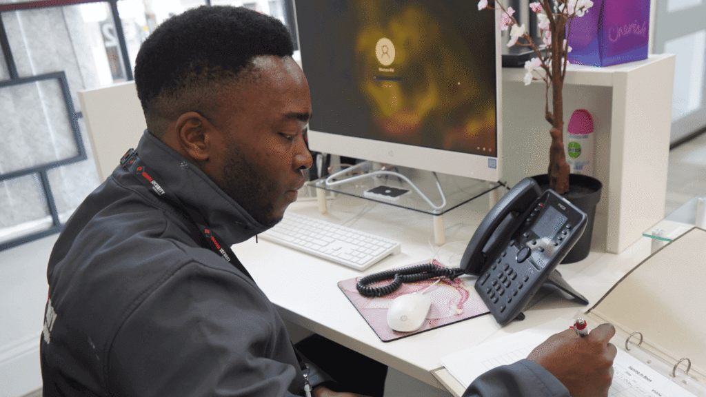 Security officer at a reception desk monitoring entry logs and phone activity, representing professional security services in the UK.