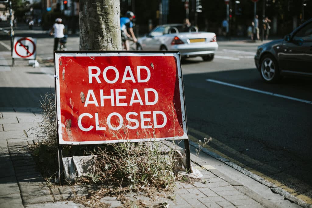 A road ahead closed banner indicating that a construction is going on nearby and traffic marshals for construction sites in Wolverhampton are managing it.