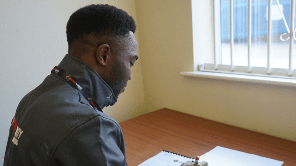 A security guard is seated at a desk, writing on papers, representing professional security services Cannock
